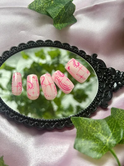 Pink heart nail art in a black ornate mirror