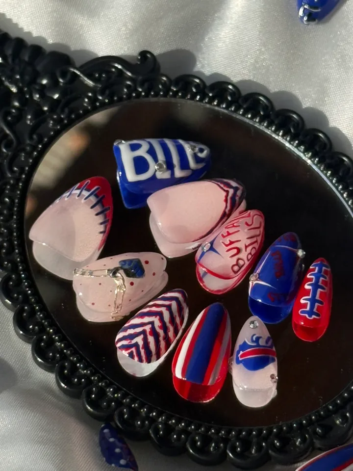 Buffalo nail art in red, blue and pink with Bills lettering, football stitching, chevrons and rhinestones displayed on a black mirror